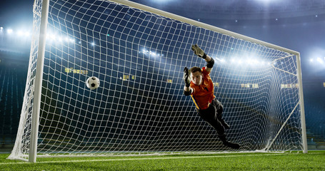 Goalkeeper is trying to save from a goal on an empty soccer stadium. No spectators on the tribunes. Stadium is made in 3d. © haizon