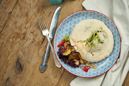 Tasty street food - Pita with tomatoes, cucumbers in blue blate on wooden background. Greek cuisine. Close up view. Shwarma