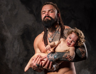 sporty brutal man holds in arms a little baby