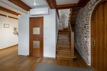 Modern contemporary loft interior of entrance hall in private house. Wooden staircase. Brick wall.