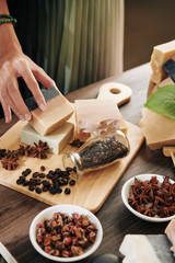 Woman putting soap bar on cutting board with coffee beans and anise flowers to make beautiful photo for her blog