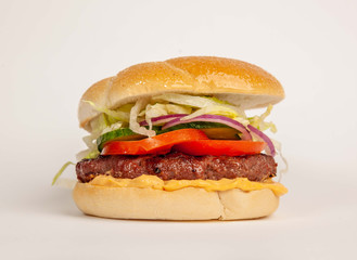 Burger with tomato and veggies over a white background