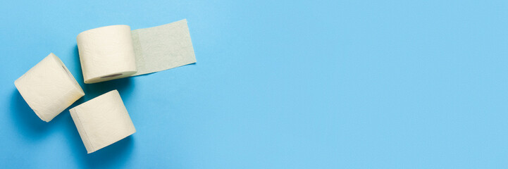 toilet paper rolls on a blue background. Flat lay, top view. Baner. Hygiene concept, deficiency, quarantine