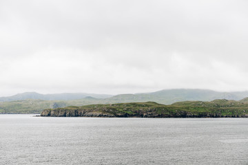 Aview over the scottish coastline from across the ocean with cloudy sky