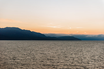 A view over a scottish coastline from across the ocean at sunset