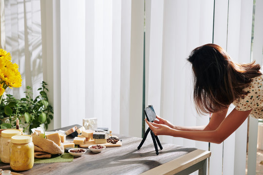 Woman setting smartphone in tripod and taking photos of handmade soap for her blog or online shop