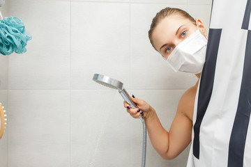 Blonde woman in medical mask standing in shower next to striped curtain