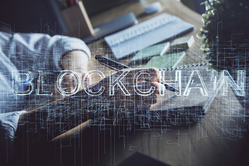 Cryptocurrency hologram, bitcoin, ico theme over hands taking notes background. Concept of blockchain. Multi exposure