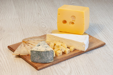 different types of cheese Roquefort cheese, walnut cheese, brie, on a wooden board.