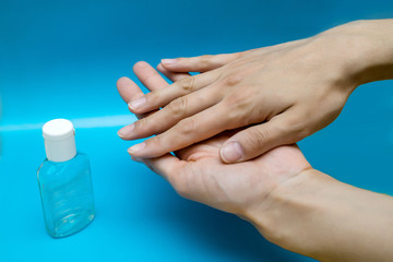 antiseptic and hands on a blue background. alcohol spray for protection against coronavirus during a pandemic