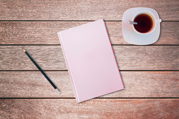 Pencil and a pink covered notebook on wooden table. Bird eye view, mock-up concept.