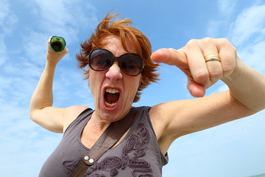 agressive woman shouting while holding a broken bottle to threaten with