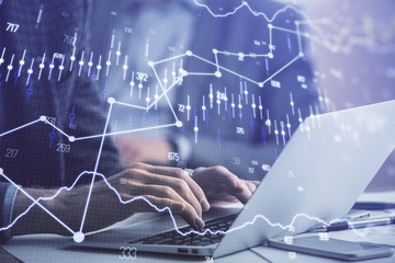 Double exposure of market chart with man working on computer on background. Concept of financial...