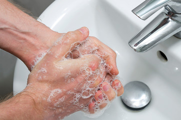 Man washing hands in the bathroom. Hands close up with hand-wash foam. Washing hands rubbing with soap man for corona virus prevention. 