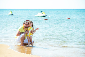 Dad and little girl play, run on the beach and fool around on the sea coast. Family vacation at sea with a child.