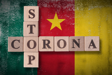 Obraz premium Flag of Cameroon with wooden cubes spelling STOP CORONA on it. 2019 - 2020 Novel Coronavirus (2019-nCoV) concept art, for an outbreak occurs in Cameroon.