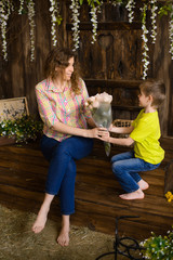 boy in shirt and jeans, gives mom bouquet of roses, sits on wooden porch, wisteria flowers