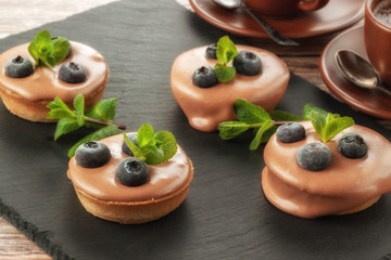 Fruit basket on a serving board and a cup of coffee on the table, fruit muffin with berries