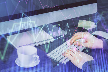 Multi exposure of graph with man typing on computer in office on background. Concept of hard work.