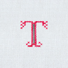 Vintage cross-stitch letter T on linen fabric