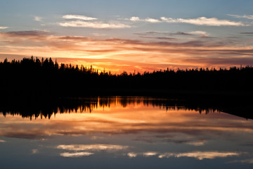 Fototapeta na wymiar sunset clouds are reflected in the calm mirror water of the lake