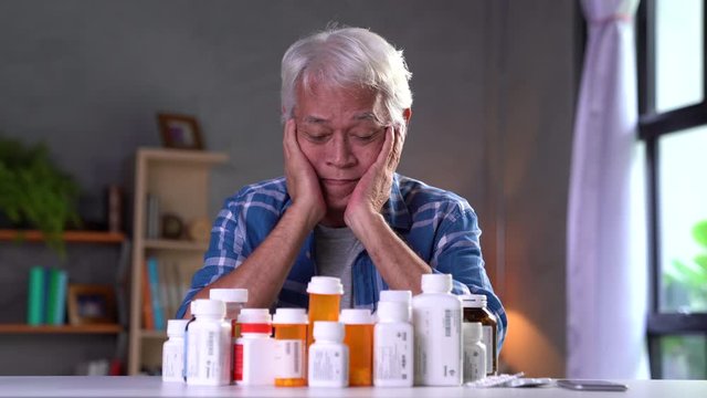 Asian senior man with his medicine bottles , senior man taking medicine .