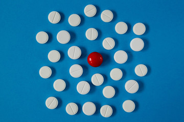 many white pills and one red on a blue background