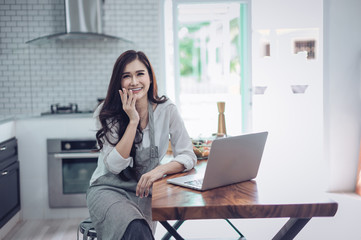 Portrait of beautiful young latin woman talking over the phone while cooking in kitchen
