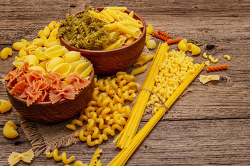 Different types of pasta in ceramic bowls. Traditional Italian food, healthy eating concept. Rustic wooden table