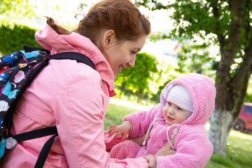 mom sits on the grass in the shade of a blossoming apple tree. plays and hugs his daughters