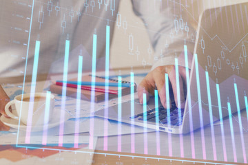 Forex graph with businessman working on computer in office on background. Concept of hardworking....