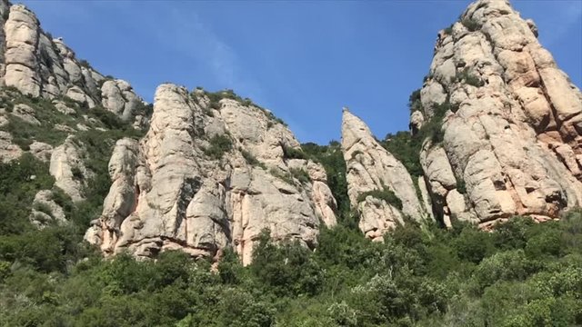 Looking up at unusual mountain spiked peaks on sunny day, Montserrat