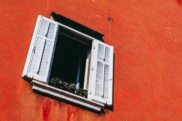 Old window with shutters in red wall