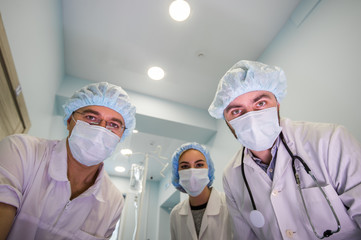 Doctors in a viral protective white masks working at emergency help looks into the camera from above like you as a patient. They working on how to stop the epidemic of the corona of the virus.