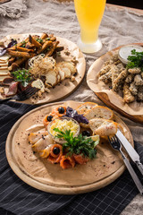 Assorted beer snacks smoked fish, cheese, roastbeef, bread croutons on wooden platter and glass of beer