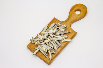 Dried salted anchovies on wooden cutting board isolated on white background