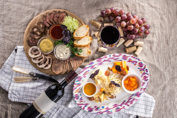 Wine appetizer set Glass of red wine, grapes, honey, cheese, meat variety, bread slices on grey table