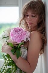 Spring Woman. Beauty Summer model girl. Beautiful Lady with pink peony on her hand. Nature Hairstyle. Natural Makeup.