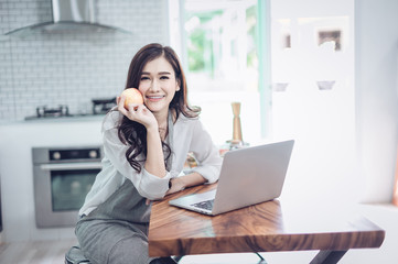 Portrait of beautiful young latin woman talking over the phone while cooking in kitchen