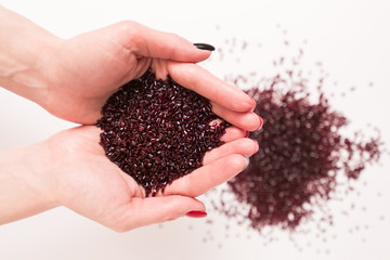 The girl holding in her hands colored plastic granules of polycarbonate close up. Red plastic...