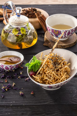 oriental honey dessert chak-chak with and poppy seeds and cup of green tea on black wooden table