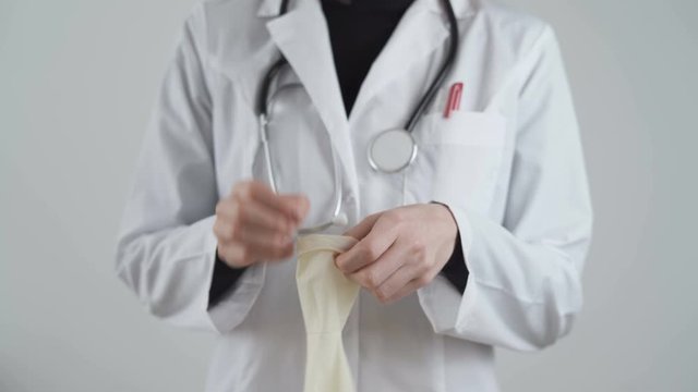 Doctor in white coat out latex glove on hand, showing how to protect yourself from coronavirus