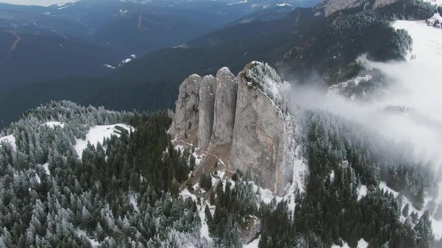 Drone flying over snowy pine forest reaching a nab, cliff