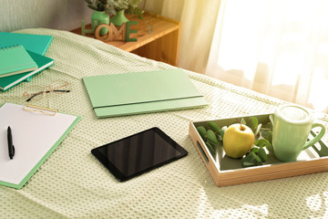 Top view of office supplies in the bed, informal working environment with laptop, notepad, tea cup. Remote work, home office, freelancer, self isolation idea