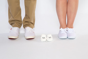 Two pairs of feet from the parents and shoes from an unborn baby