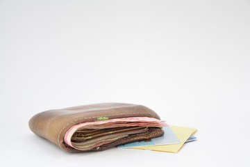 Brown men's wallet with money placed on a credit card, placed on a white background