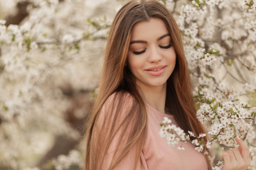 Naklejka premium Portrait of pretty young girl in the garden of blossom cherry trees. Spring time