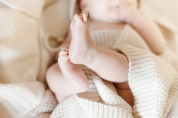 Small children's legs look out from under a striped plaid. Family happiness. Love.