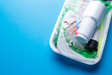 Set of plastic waste in a packed tray on a blue isolated background. The problem of ecology and environmental pollution.
