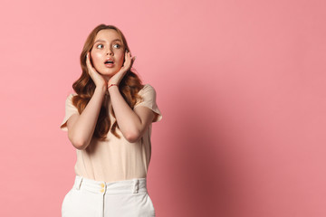 Fototapeta premium Woman surprise holds cheeks by hand . Presenting your product. Isolated on pink background. copy space left